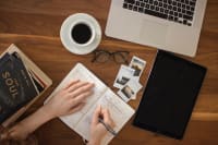 content-marketing-writer Writer at desk from above with laptop, tablet, pen, paper, and coffee